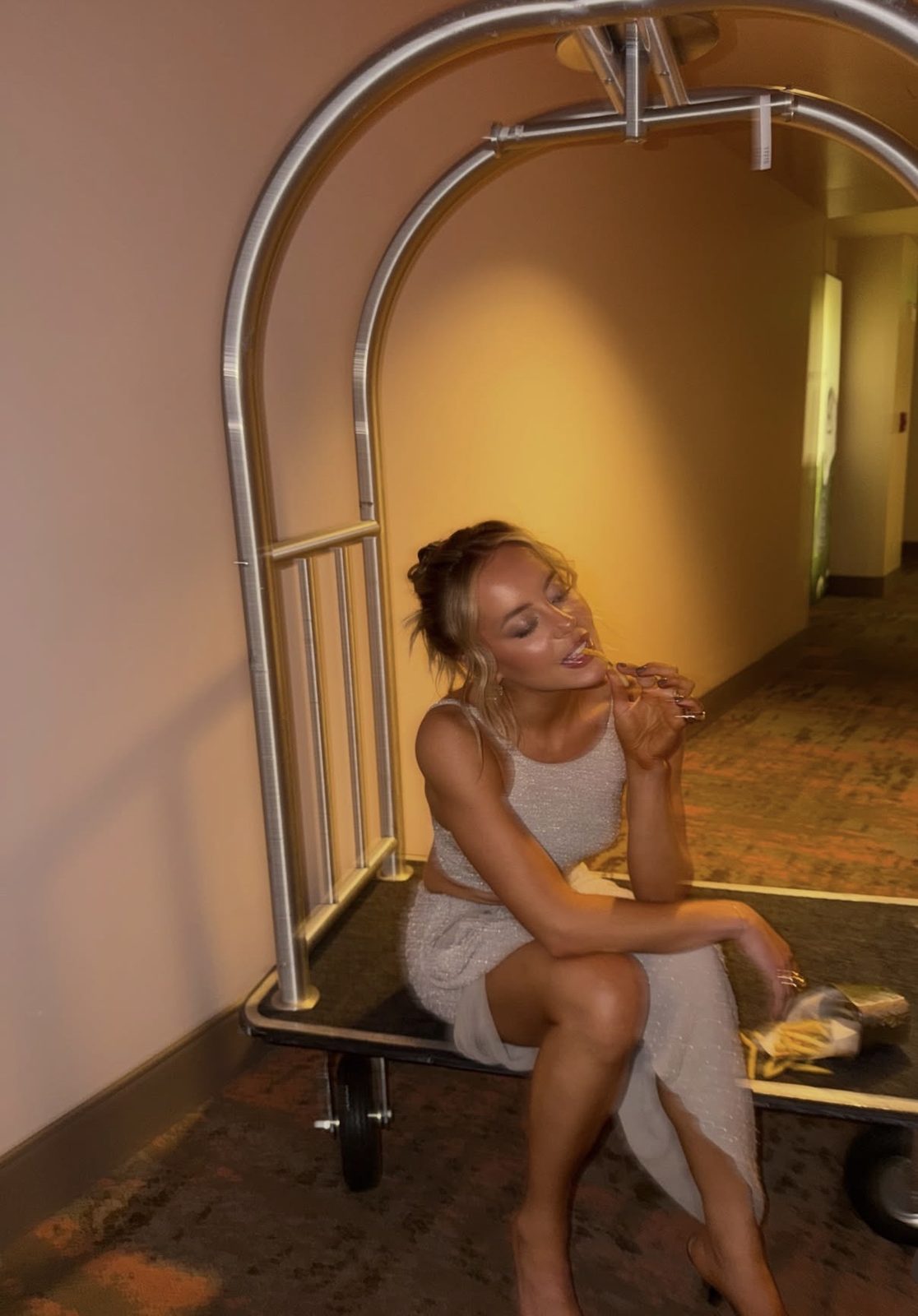 Brooke Baevsky sitting on a hotel luggage cart